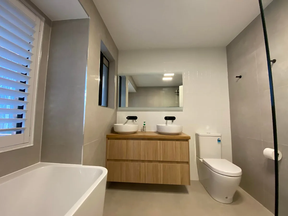 Bathroom with twin basins on a timber vanity, a freestanding bath and plantation shutters