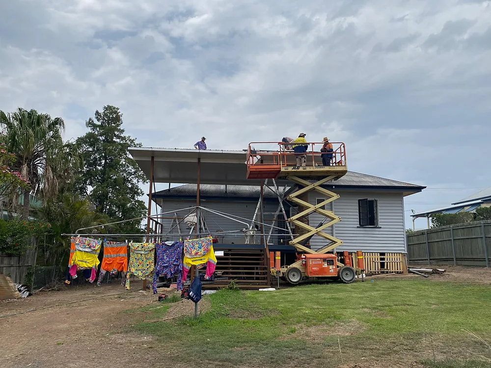 Old Queenslander on stumps with a scissor lift beside it during a lift and shift