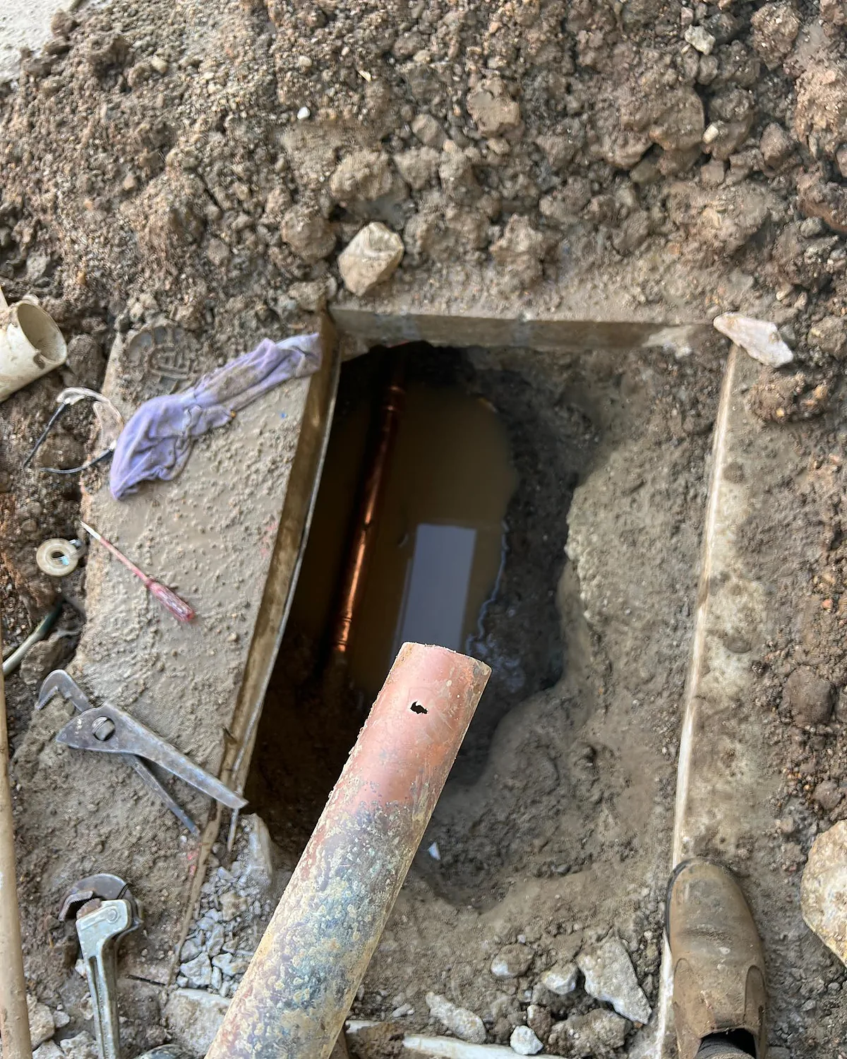 Dug-out sewer inspection point with pipe and tools